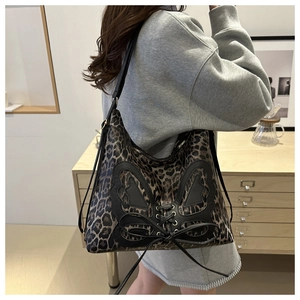 Detail of leopard print tote bag featuring a black leather bow and drawstring hardware