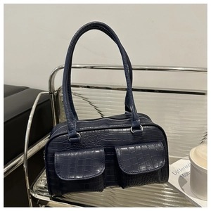 Detail of dark blue crocodile texture handbag with dual front pockets and silver hardware