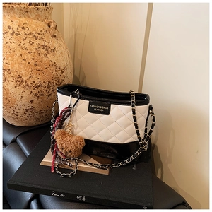 Détail du sac seau matelassé avec bandoulière chaîne dorée et breloque ours peluche