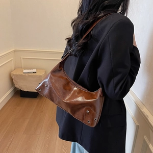 Borsa sottobraccio in pelle cerata marrone vintage con borchie indossata dal modello