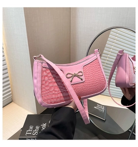 Macro shot of pink crescent bag with crocodile pattern and metallic bow detail