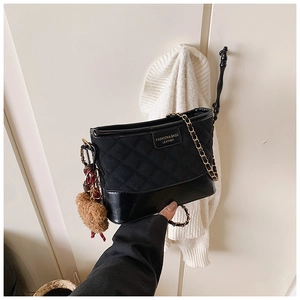 Détail du sac seau noir matelassé avec bandoulière chaîne et breloque ours en peluche