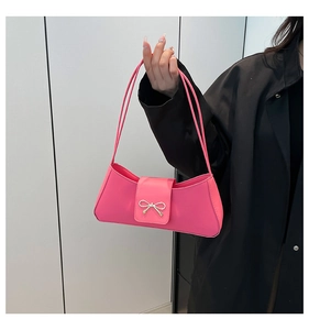 Detail of hot pink baguette bag featuring silver metal bow and slim double shoulder straps