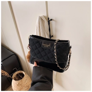 Détail du sac seau matelassé noir avec plaque logo dorée et bandoulière en chaîne