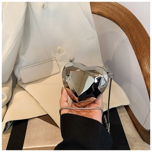 Gros plan d'un sac de soirée argenté en forme de cœur avec surface métallique coupée