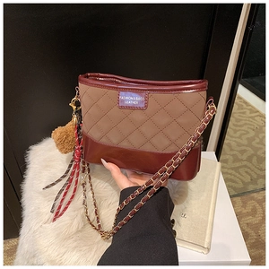 Détail du sac seau matelassé avec bandoulière en chaîne dorée et breloque pompon doux