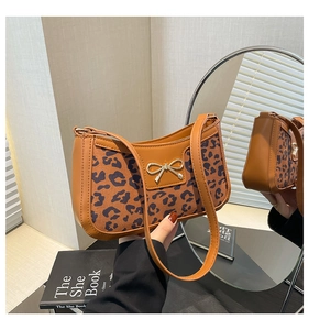 Detail of leopard print crescent bag with golden bow hardware and faux leather strap