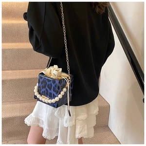 Detail of blue leopard print bucket bag with pearl handle and golden chain strap