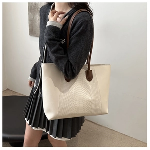 Close-up of cream tote bag featuring snakeskin texture and brown leather straps