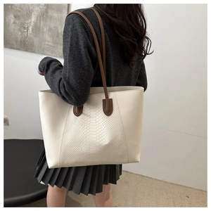 Detail of ivory tote bag with snake-pattern texture and dark brown shoulder strap
