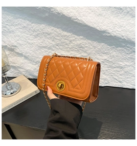 Detailed view of brown quilted crossbody bag with gold twist lock and metal chain strap