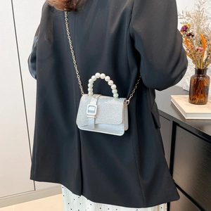 Silver sequin mini flap bag with white pearl handle and gold chain strap shown on model