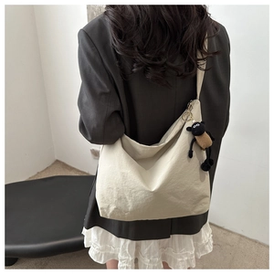 Detail view of large beige canvas hobo bag with a cute black sheep plush charm accessory