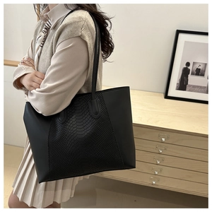 Close-up of black tote bag featuring embossed snake pattern and matte texture details