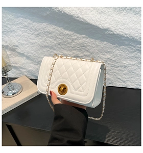 Detail of white quilted crossbody bag with golden chain strap and round metal twist lock