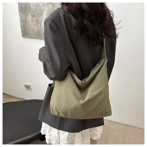 Detail of olive green slouchy nylon tote bag with pleated texture on female model