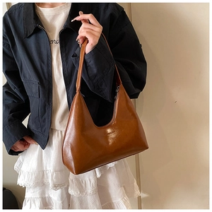 Detail of vintage brown crescent bag with embossed logo and glossy leather texture