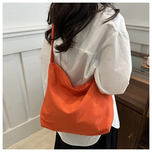 Side view of large orange canvas tote bag with metal zipper worn by a model