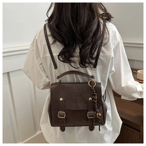 Detailed back view of a retro brown PU leather backpack with buckle straps and woven charm