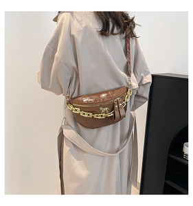 Détail du sac de poitrine marron à motif crocodile avec chaîne dorée et bandoulière