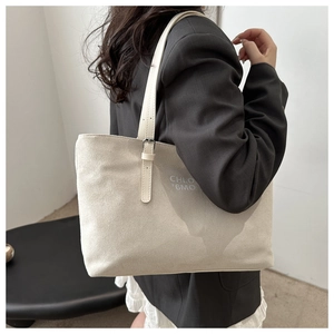 Detail of light beige suede tote bag with gray logo lettering and slender shoulder strap