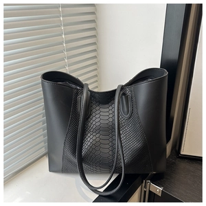 Detail of black tote bag showing python skin texture contrast with matte leather finish