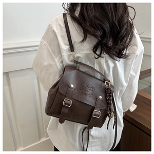Close-up of a retro dark brown leather backpack with belt straps and logo detail