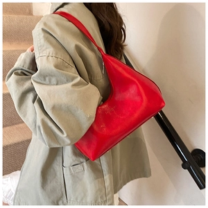 Close-up of vibrant red crescent underarm bag in a minimalist indoor setting