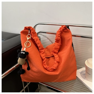 Detail of vibrant orange fabric tote bag with ruffled handles and plush sheep keychain