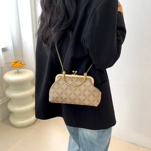 Vintage beige shell crossbody bag with clover patterns and gold chain handle on a model
