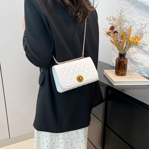 Chic white quilted crossbody bag with gold hardware worn as a stylish shoulder bag