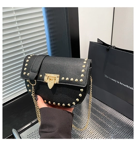 Detail of black pebbled leather handbag with gold studs, chain strap and push-lock buckle