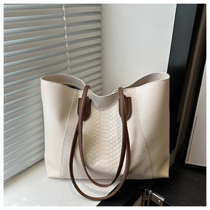 Close-up of cream tote bag featuring snake pattern texture and dark brown handles