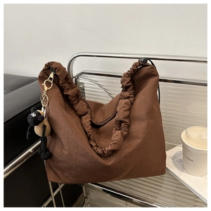 Detail of dark brown nylon tote with ruched cloud strap and cute sheep pendant