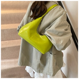 Detailed macro view of the glossy green patent leather texture and secure zipper on the crescent bag
