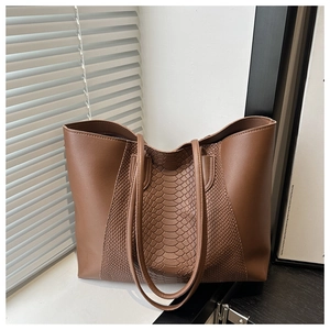 Detailed view of brown tote bag featuring snakeskin embossed leather and smooth texture