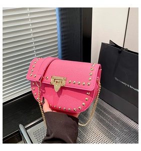Detail of pink saddle bag featuring pebbled leather, gold studs, and chain strap