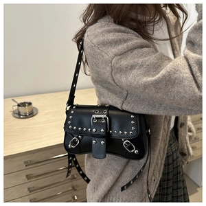 Detail of black crossbody bag featuring silver metal rivets and adjustable shoulder strap