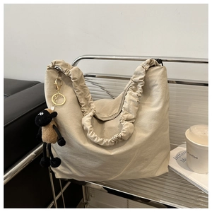 Detail of beige large tote bag featuring pleated wide shoulder strap and cute sheep charm