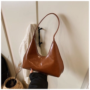 Detailed view of brown crescent hobo bag featuring the embossed logo on matte leather