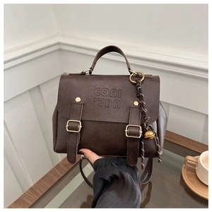 Detail of vintage coffee brown backpack with dual buckles and decorative bell pendant