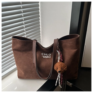 Detailed shot of brown suede tote bag with letter print and a cute teddy bear charm