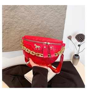 Détail du sac de poitrine rouge embossé croco avec logo zèbre doré et chaîne épaisse