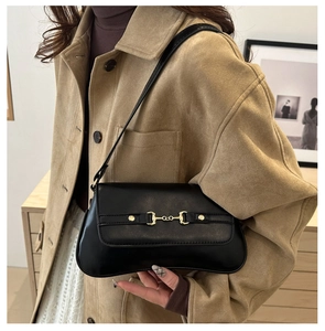 Detail of vintage black matte leather underarm bag with gold horsebit buckle on a model