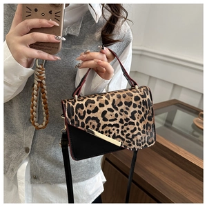 Detail view of leopard print flap bag with gold metal trim and black leather base