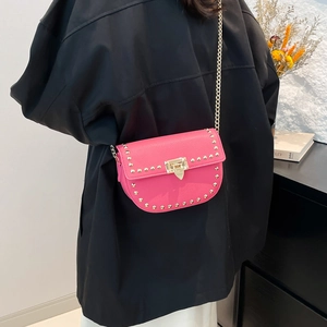 Chic rose pink saddle bag with golden studs and chain strap worn by a model