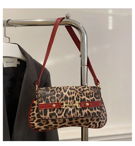 Close-up of leopard print shoulder bag with red strap and golden horsebit detail