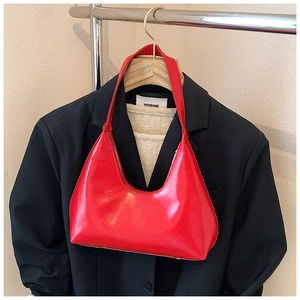 Detail of red crescent hobo bag with Stashion logo hanging on a clothing rack