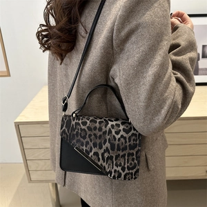 Chic leopard print crossbody bag with gold metal trim worn over a beige suit jacket
