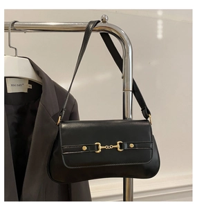 Close-up of black leather baguette bag with vintage golden horsebit buckle hardware